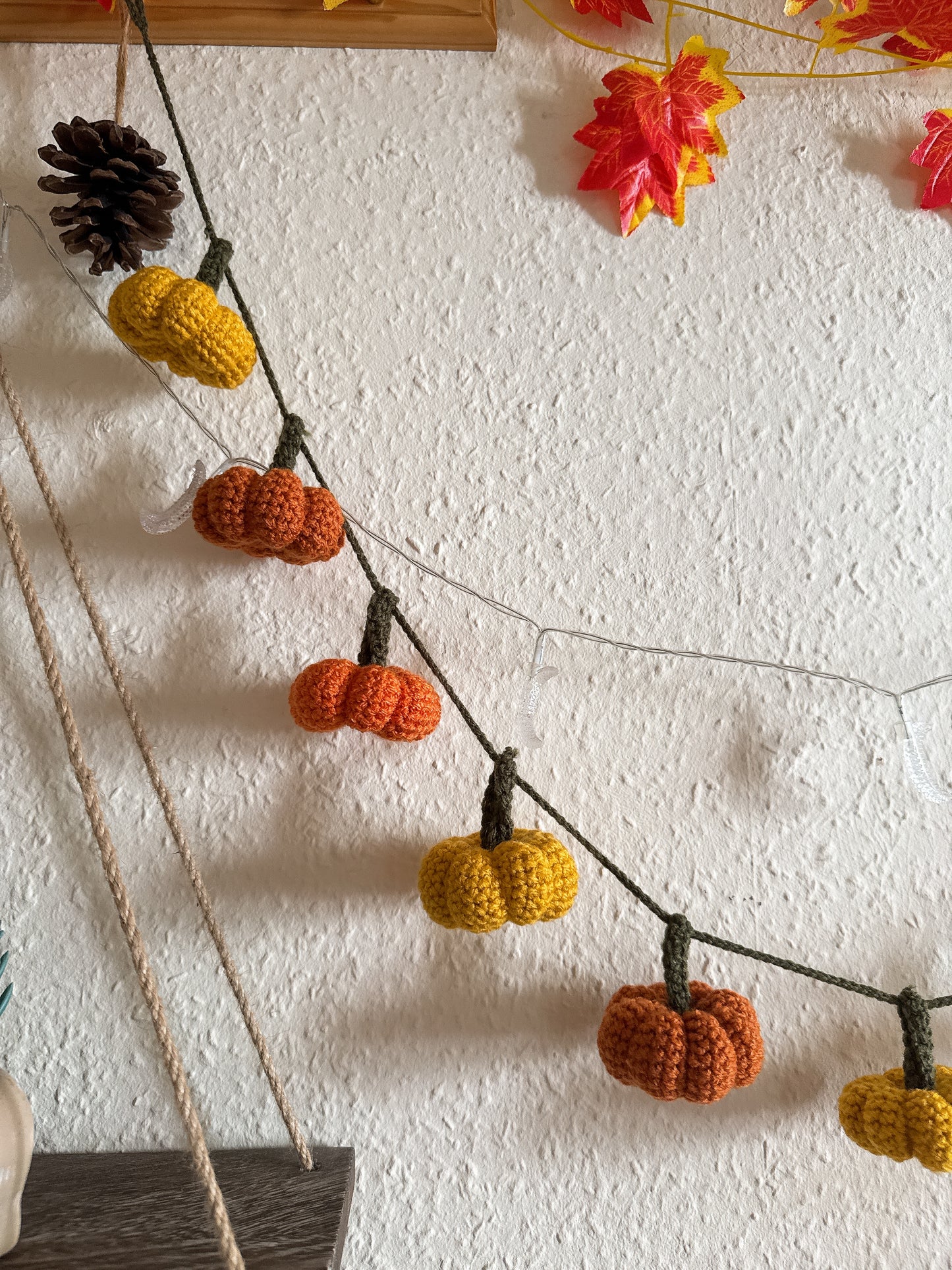 Beginners Friendly Crochet pumpkin garland pattern featuring handmade orange pumpkins with green stems on a rustic string, perfect for autumn, Halloween, and Thanksgiving decor