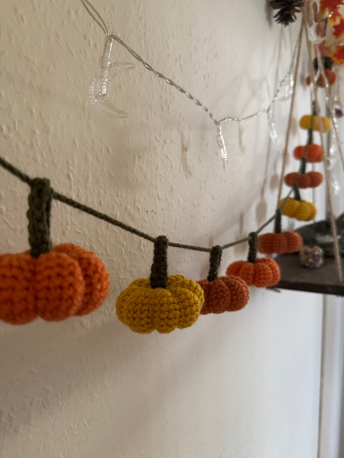 Beginners Friendly Crochet pumpkin garland pattern featuring handmade orange pumpkins with green stems on a rustic string, perfect for autumn, Halloween, and Thanksgiving decor