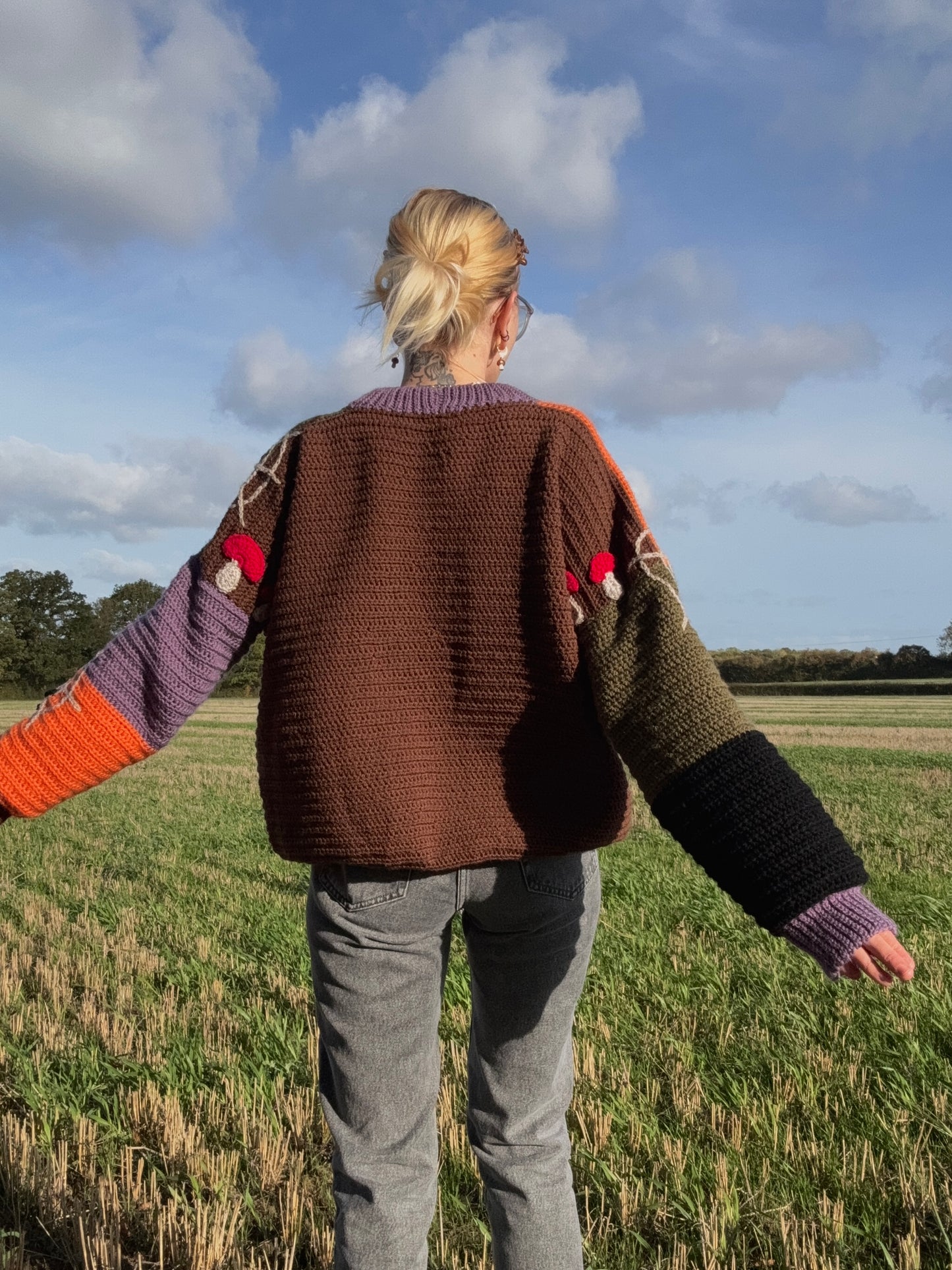 Cozy autumn sweater crochet pattern from the back with mushroom appliques on the arms. Beginner-friendly customizable in size crochet pattern with step-by-step photo tutorials. Picture from the back.