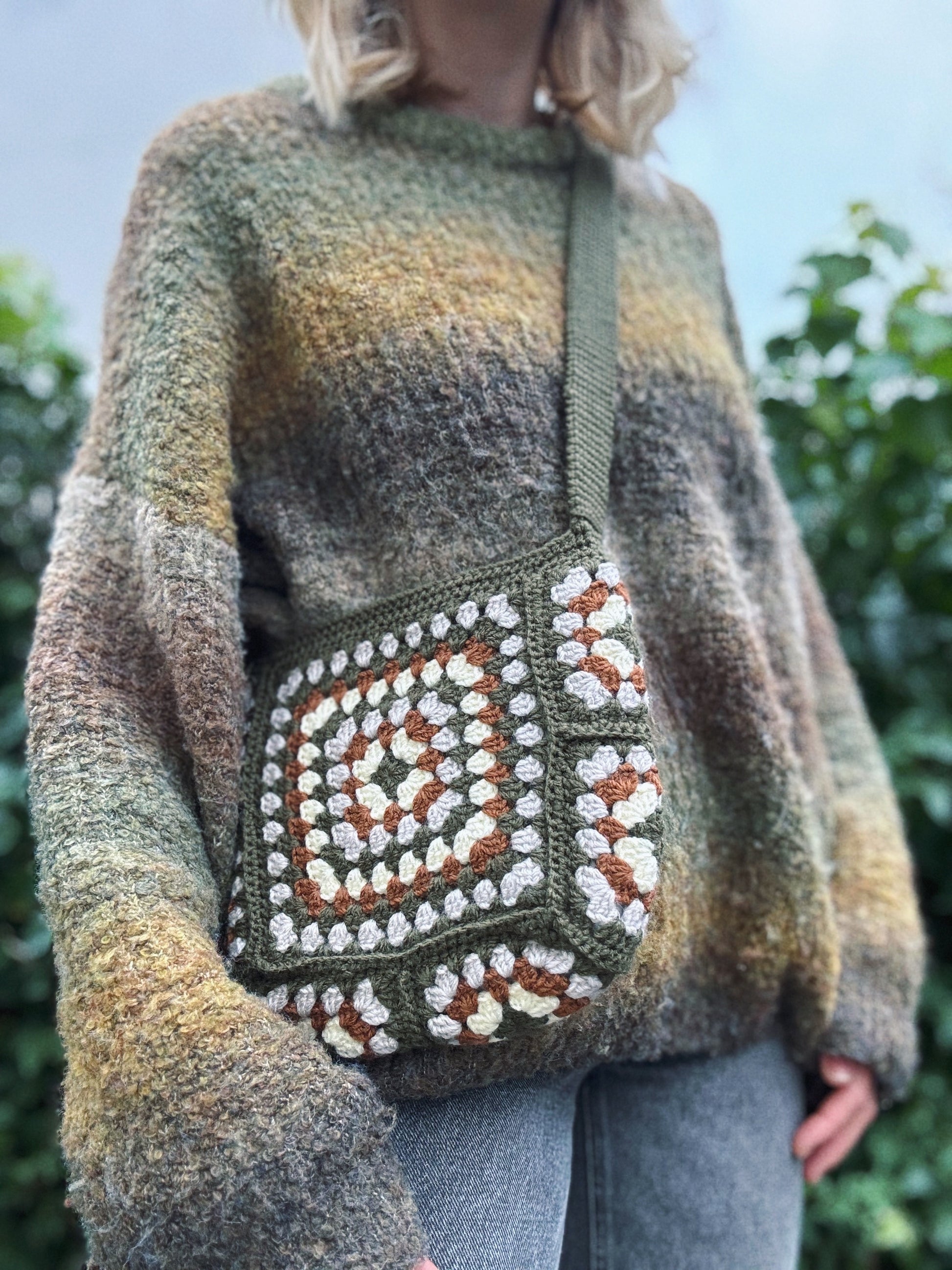 Crochet Pattern Of Granny Glam Bag Crochet Pattern with Grey, Dark Green Colour that owner of shop wears it outside near the tree, front.