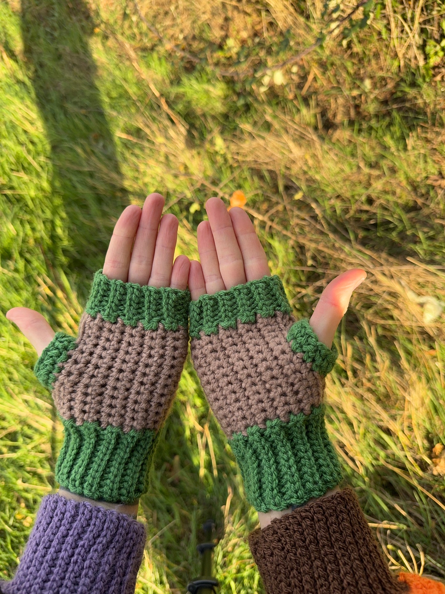 Autumn fingerless gloves crochet pattern – textured handmade wrist warmers in orange, green and brown colors. Easy beginner crochet project with a step-by-step photo tutorials. Picture shows the palm side of the glove.