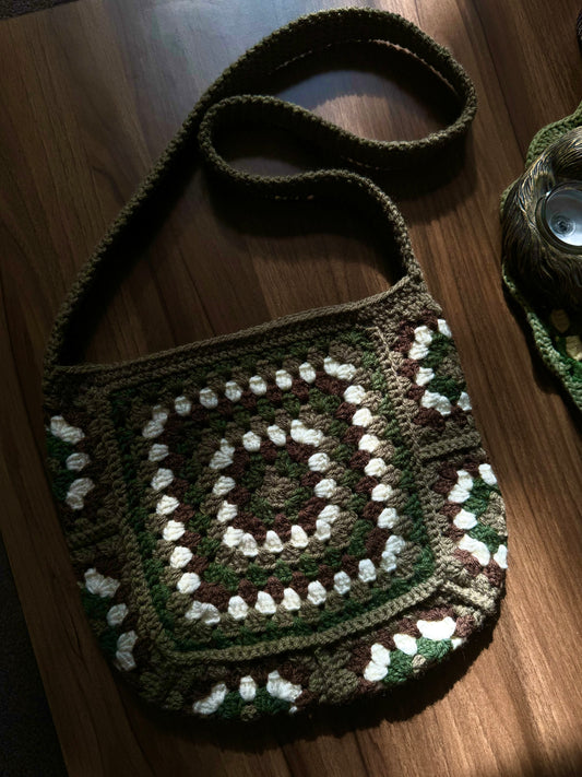 Crochet Pattern Of Granny Glam Bag Crochet Pattern with Grey, Dark Green Colour laying on the wooden desk.