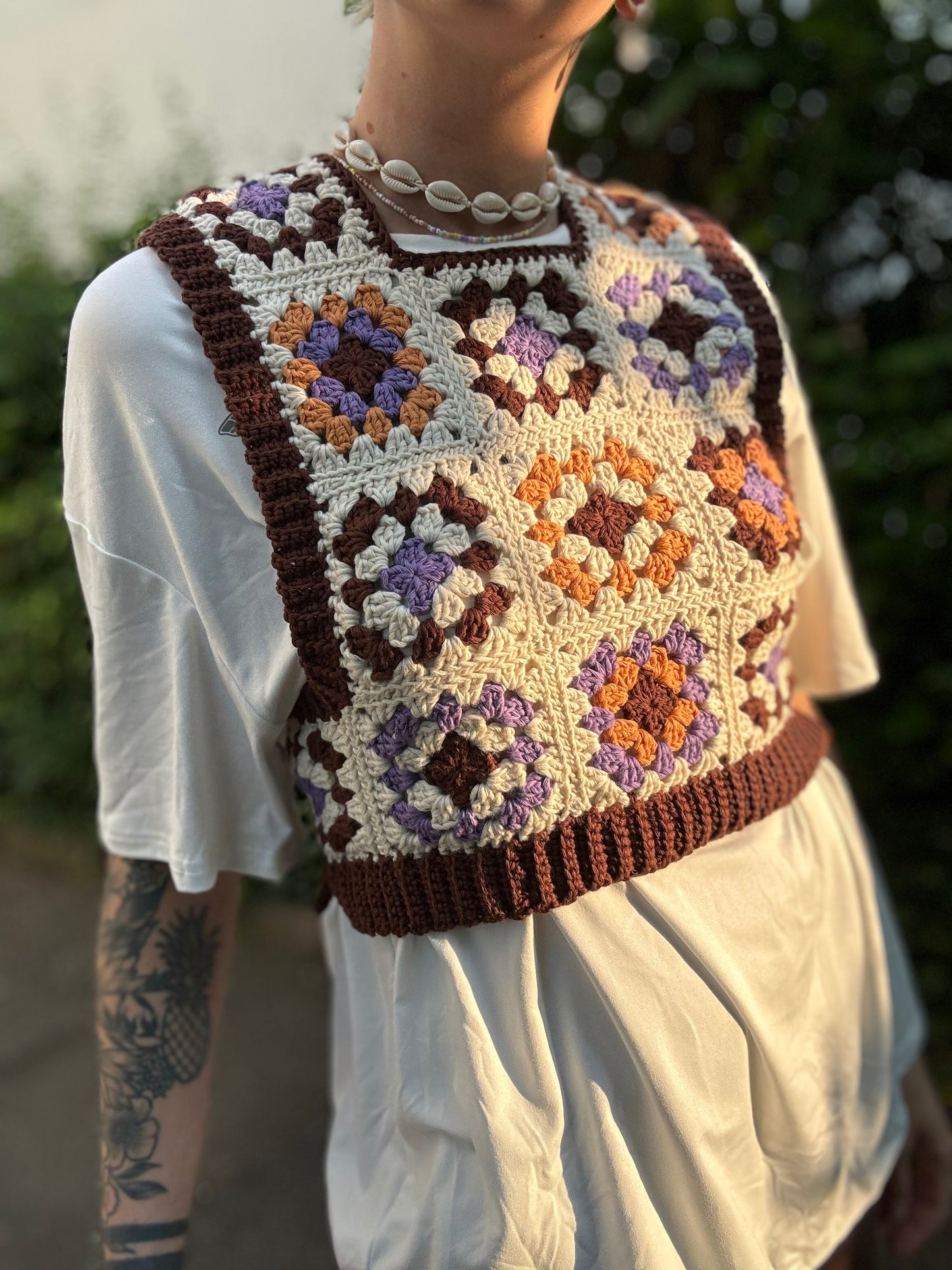 Crochet Pattern Picture of granny square patchwork top which crochet business owner wears in on top of white shirt outside.