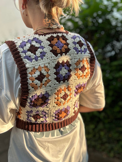 Crochet Pattern Picture of granny square patchwork top which crochet business owner wears in on top of white shirt outside from the back.