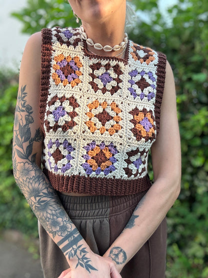 Crochet Pattern Picture of granny square patchwork top which crochet business owner wears in on top of white shirt outside.