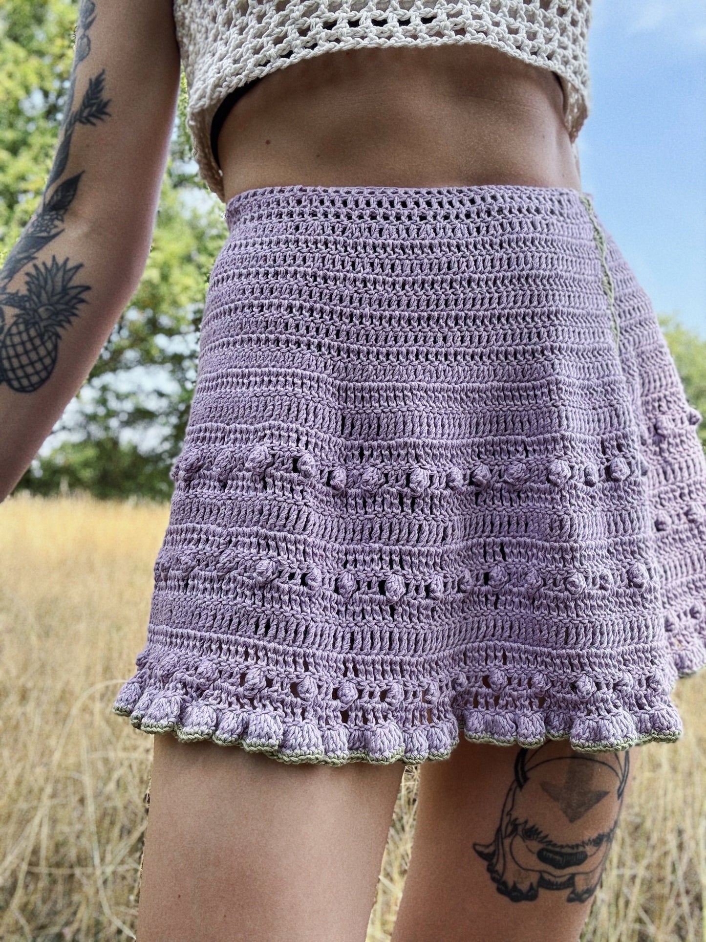 Summer crochet wrap skirt displayed outdoors from the front in purple color, lightweight for summer, customizable.
