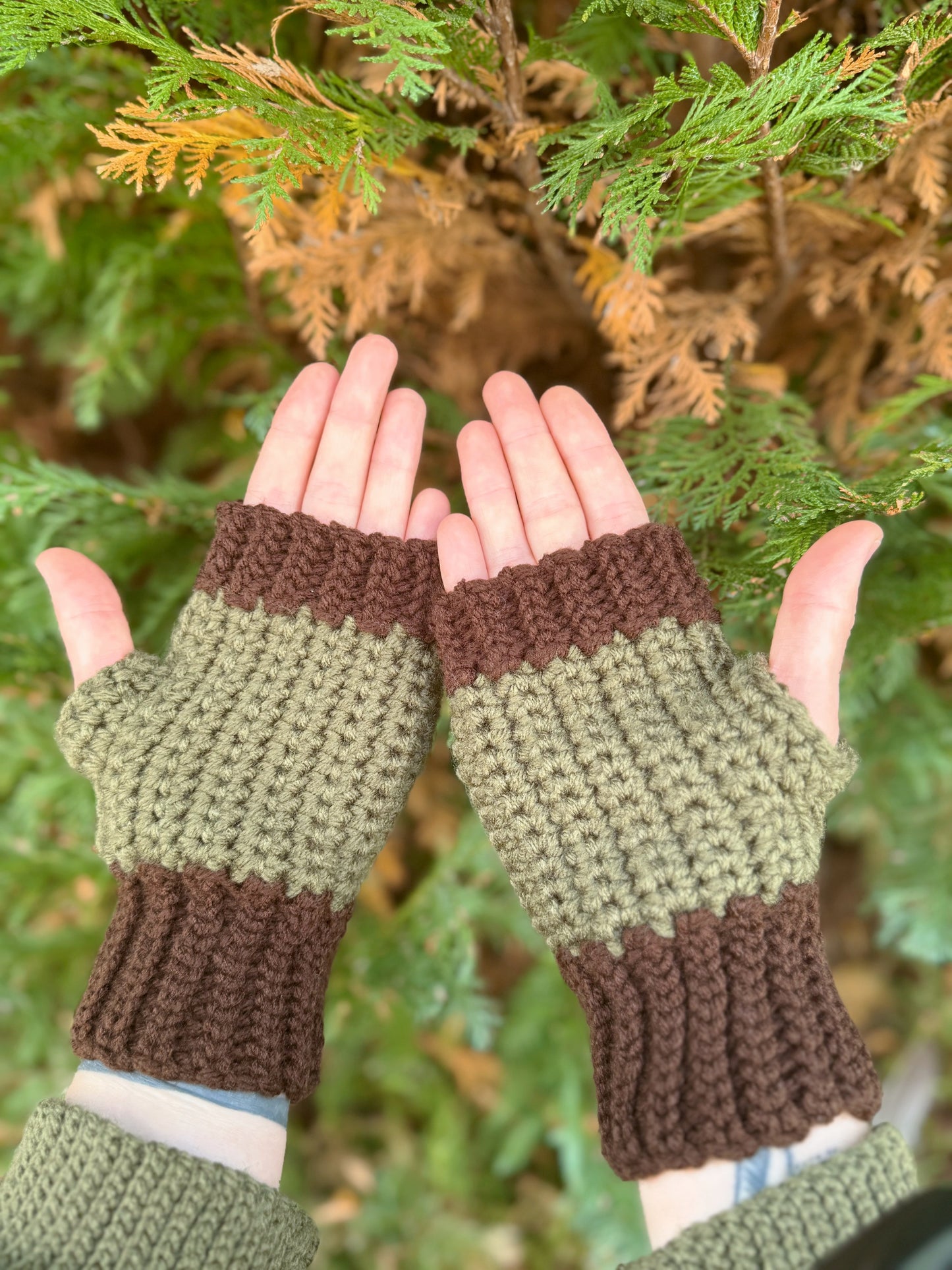 Fingerless gloves crochet pattern – textured handmade wrist warmers. Picture shows the palm side of the gloves in forest green and brown color. Easy beginner crochet project with a step-by-step photo guide.