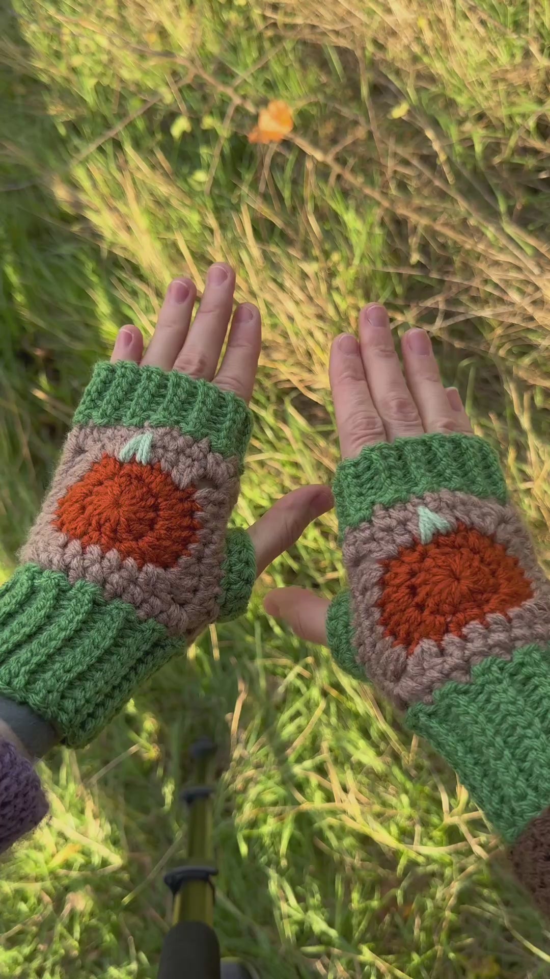 Autumn fingerless gloves crochet pattern – textured handmade wrist warmers in orange, green and brown colors. Easy beginner crochet project with a step-by-step photo tutorials. Picture shows the palm side of the glove.